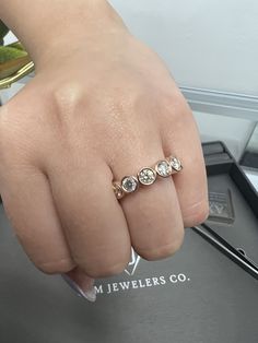 a woman's hand with three diamond rings on top of her finger, next to a pen