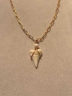 a necklace with an angel charm hanging from it's center on a gold chain