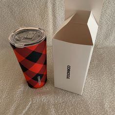 a red and black plaid cup next to a cardboard box