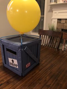 a yellow balloon sitting on top of a blue crate in the middle of a room