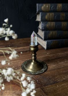 a small candle holder sitting on top of a wooden table next to books and flowers