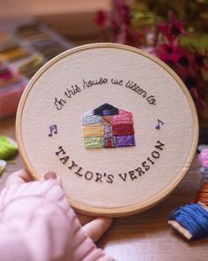 a hand holding a wooden embroidery kit with the words, i'm wild house we listen to tailor's version on it