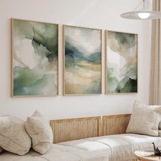 three paintings hang on the wall above a couch