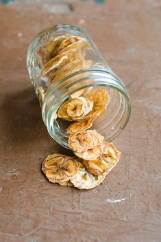 a glass jar filled with dried bananas on top of a wooden table