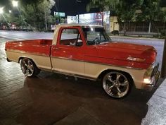 an old red and tan truck parked on the street