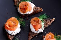 four slices of bread with smoked salmon and cream cheese on top, garnished with dill