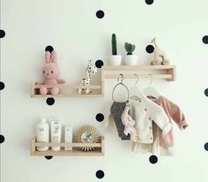 two wooden shelves with baby items on them in front of a polka dot wallpaper