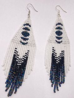 These handmade beaded earrings feature a lovely moon phase pattern along with a lovely fringe with of white and a matte blue. Moon Fringe Earrings, White Fringe Tassel Earrings For Festivals, White Beaded Fringe Earrings For Festival, White Bohemian Fringe Earrings, White Beaded Fringe Festival Jewelry, Festival White Beaded Fringe Jewelry, White Dangle Tassel Earrings For Festivals, Handmade White Bohemian Tassel Earrings, Bohemian White Beaded Fringe Earrings