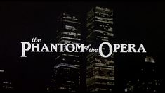 the phantom of the opera logo in front of tall buildings at night with lights on