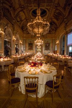 a fancy dining room with chandeliers and tables set for dinner in the center