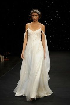 a woman in a white dress walking down a runway