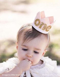 a baby girl wearing a pink and gold birthday hat with the words best seller on it