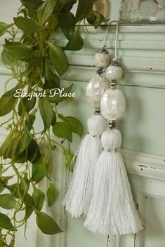 white tasselled ornaments hanging on a wall next to a potted green plant