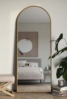 a large mirror sitting on top of a wooden floor next to a white bed in a bedroom