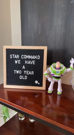 a toy buzz lightyear standing next to a sign that says star command we have two year old