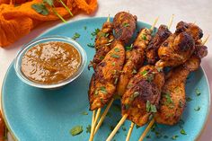 chicken skewers with dipping sauce on a blue plate