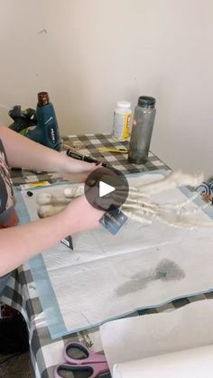 a woman sitting at a table cutting paper with scissors and glue on top of it