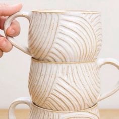 two white coffee mugs sitting next to each other on top of a wooden table