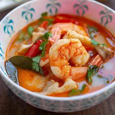 a bowl filled with shrimp and vegetables on top of a wooden table