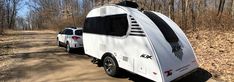 an rv is parked on the side of a dirt road in the middle of trees