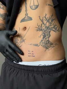 a man with tattoos on his stomach and hands in black gloves holding an apple tree