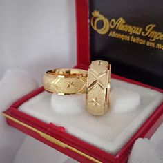 two gold rings sitting in a red box