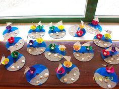 paper boats and seashells are placed on the sand in front of a window