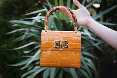 The Gaia Top Handle Mini Bag made of crocodile-embossed leather in a caramel-orange color. Bamboo handle, clasp, gold-toned hardware. Basic Essentials, Orange Caramel, Caramel Color, Elevate Your Look