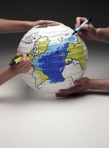 two hands holding a paper lantern with the earth painted on it and a marker in each hand