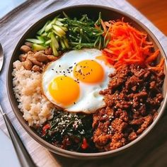 a bowl filled with rice, meat and veggies next to a fork on top of a table