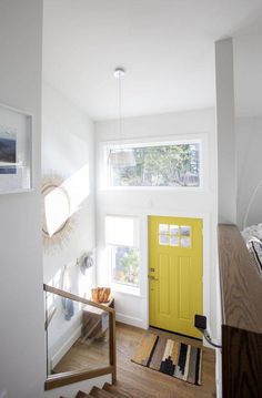 a bright yellow door sits in the corner of a white room next to a staircase