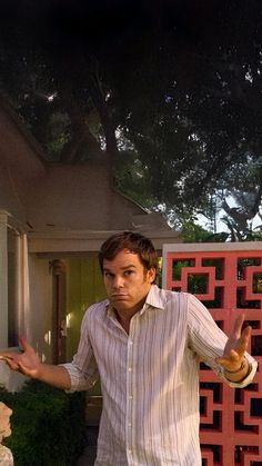 a man standing in front of a house with his hands out to the side while holding something