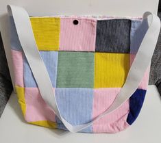 a multicolored handbag sitting on top of a white table next to a gray chair