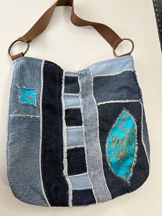 a handbag made out of old jeans with patches on the front and side pockets