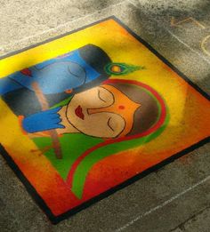 a colorful painting on the ground in front of a parking meter with a person wearing a hat