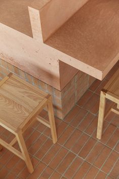 two wooden stools sitting next to each other on a tiled floor in front of a counter