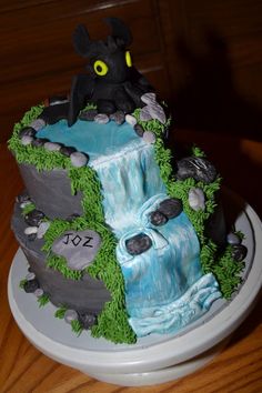 a cake that is on top of a plate with rocks and grass around it, in the shape of a waterfall