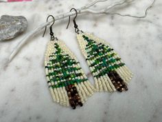 a pair of beaded earrings sitting on top of a white table next to a rock