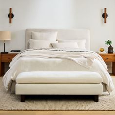 a bed with white sheets and pillows in a room