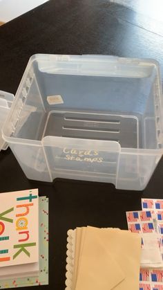 plastic storage containers are sitting on a table next to some cards and envelopes,