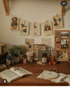 a wooden table topped with lots of pictures and papers on it's wall next to a potted plant