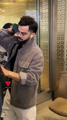 a man is looking at his cell phone while standing in front of a glass door