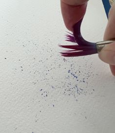 a person is using a brush to paint something white with blue and purple flecks