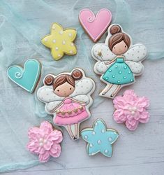 decorated cookies are arranged in the shape of angels and flowers on a white wooden table