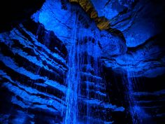 a waterfall is lit up in the dark with blue lights on it's sides