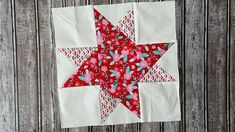 a red and white quilted star hanging on a wooden wall