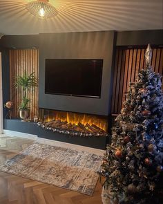 a living room with a christmas tree in the corner and a flat screen tv above it