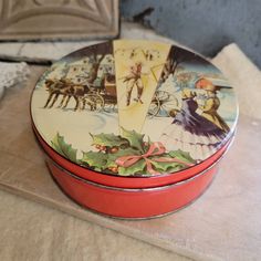 a red tin with a christmas scene on it sitting on top of a wooden table