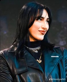 a woman with black hair wearing a leather jacket