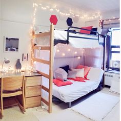 a bunk bed with white sheets and red pillows in a room decorated with string lights